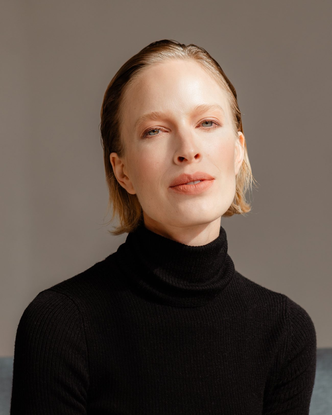 Portrait of a woman in a black roll-neck, natural skin, soft orange lip