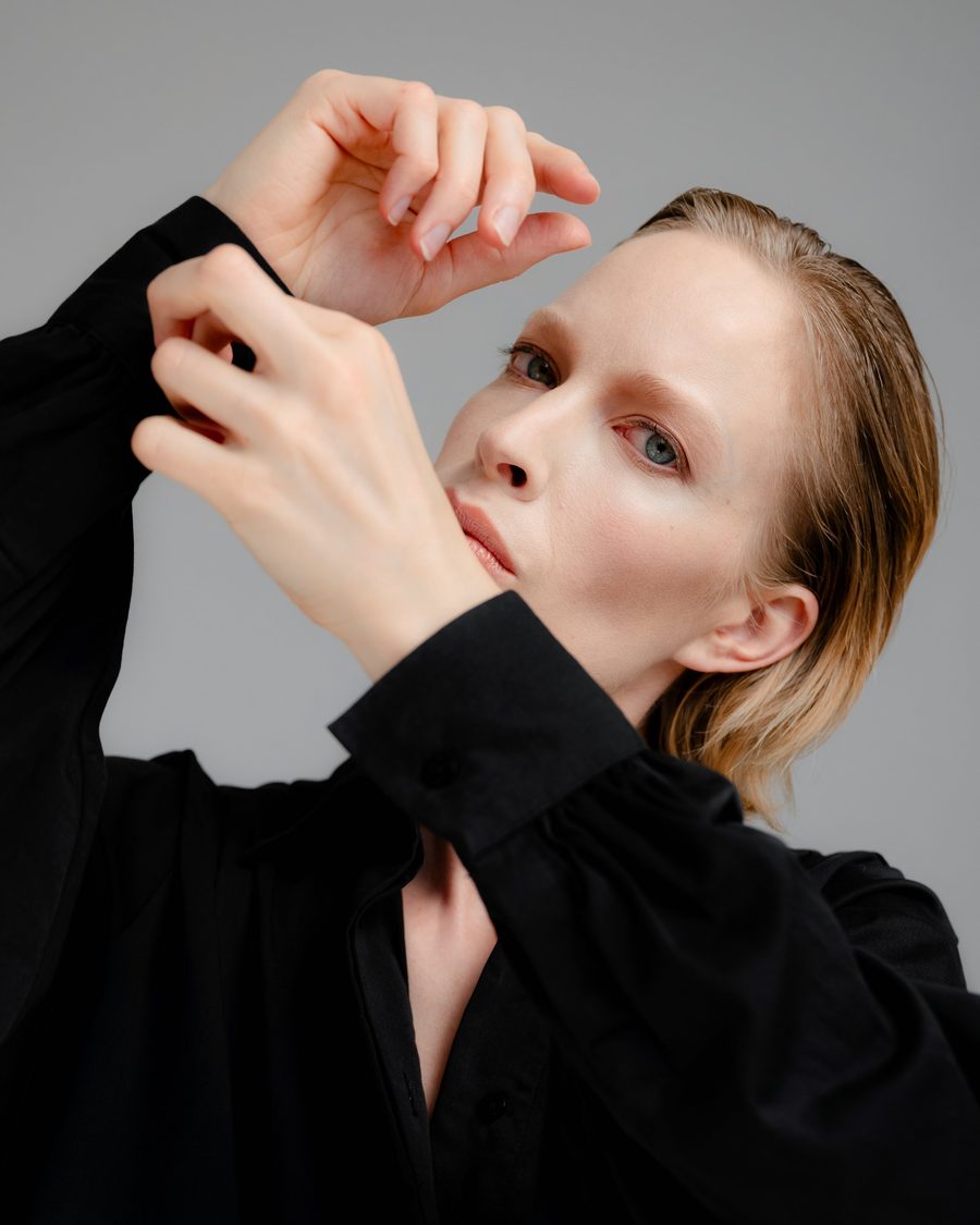 Woman in a black shirt, arms raised around her face