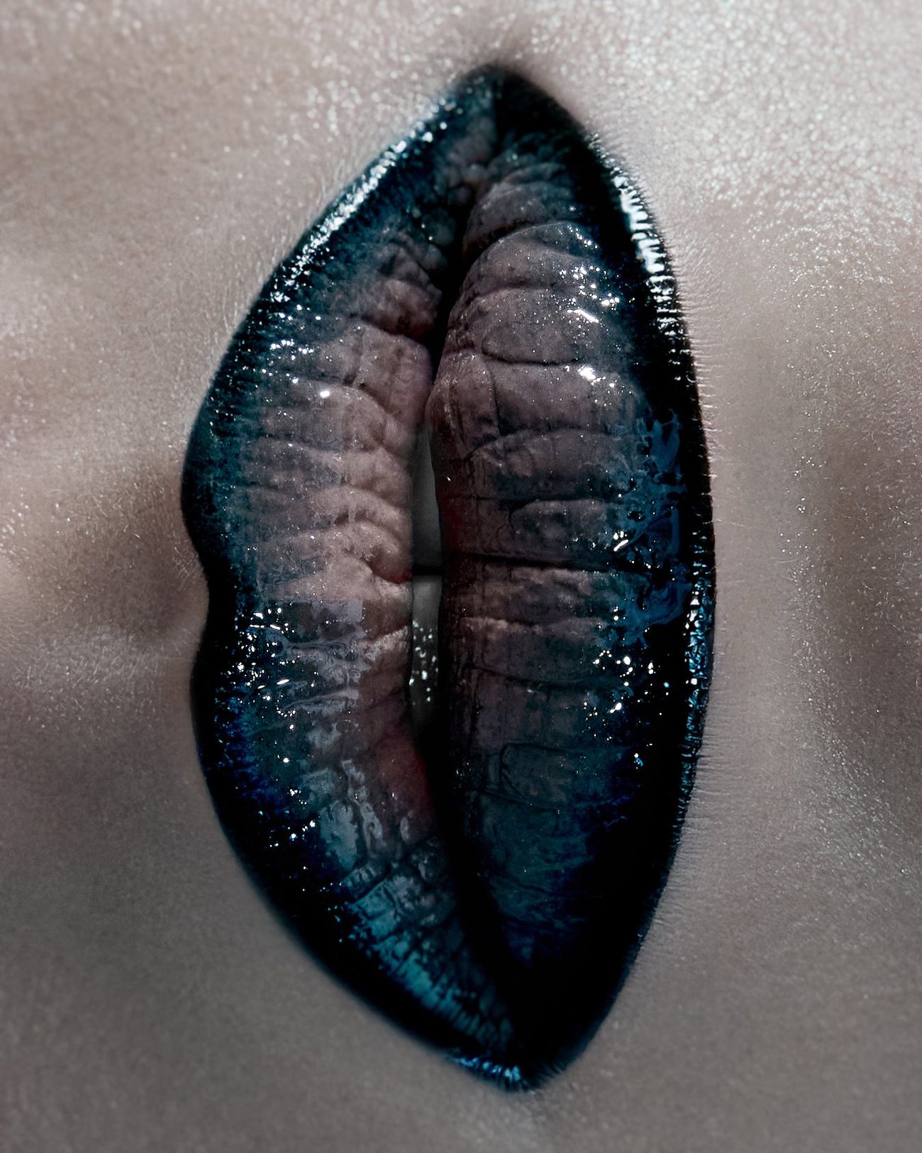 Close-up of lips painted in glossy blue-black