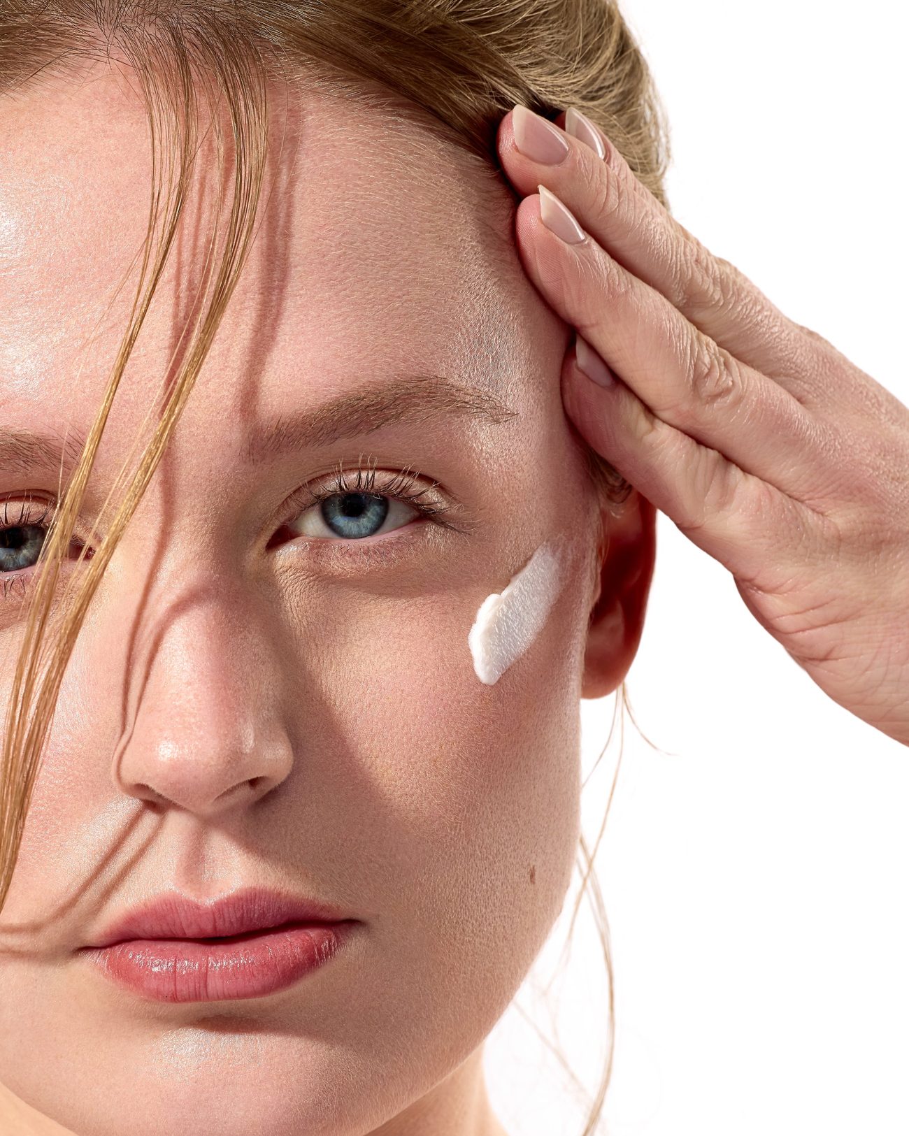 Close-up of a freckled face with a stroke of cream on the cheek