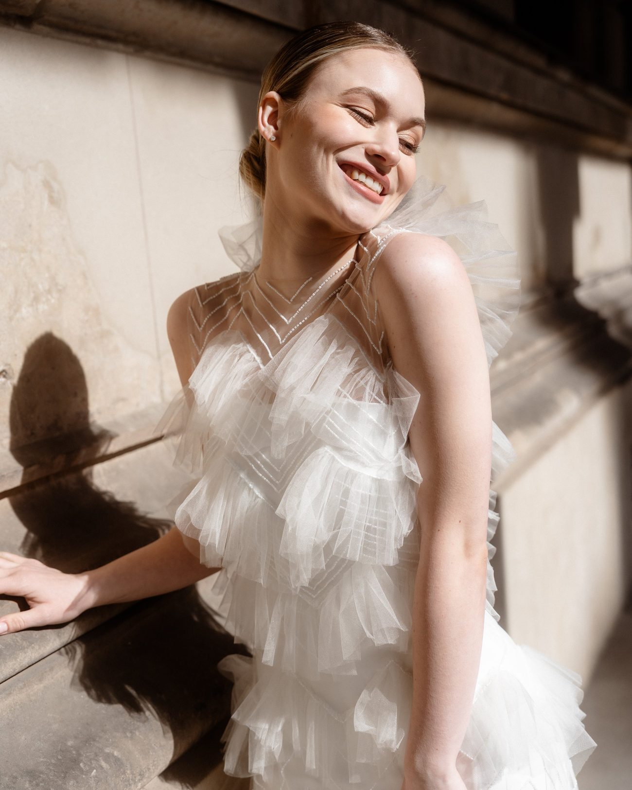Bride in a tulle dress laughing in the sun
