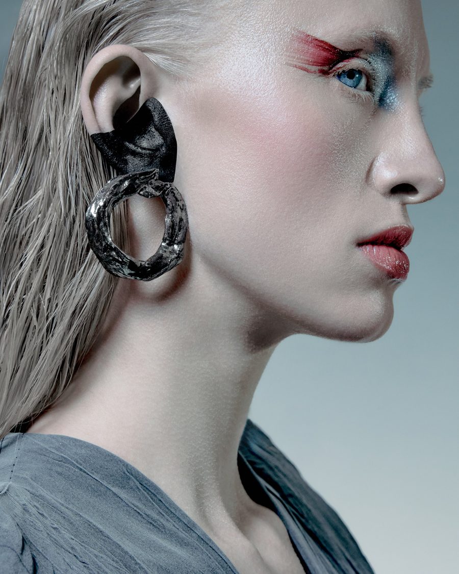 Profile with a red band of colour across the eye and a large black earring