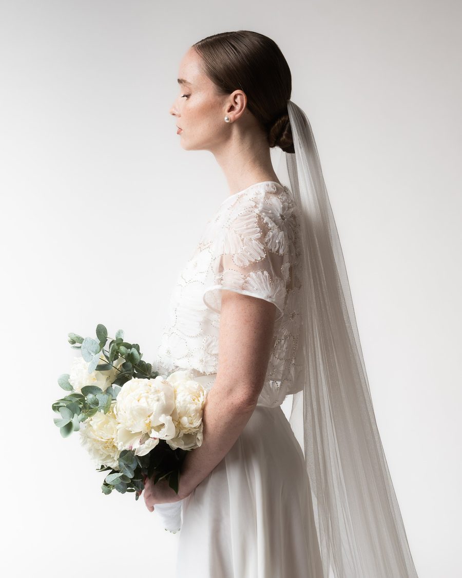 Bride in profile with a long veil and a bouquet