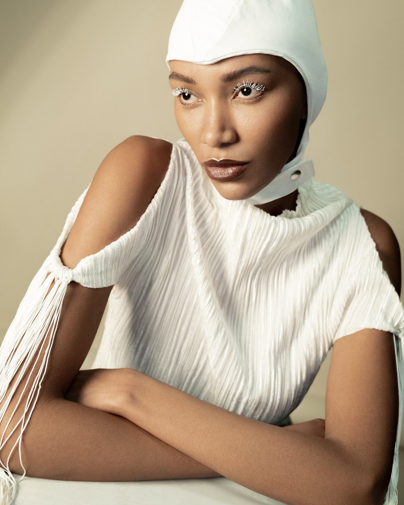 Model in a white hood and pleated top, white lashes